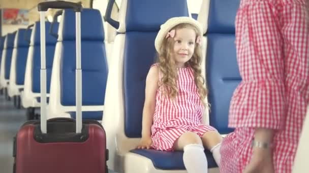 Fiatal nő a kis lányát veszi a bőröndöt, és elhagyja a vonat — Stock videók