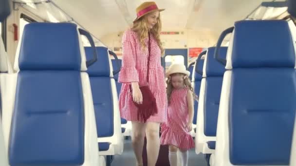Linda niña con su mamá entra en el vagón de tren a sus asientos — Vídeo de stock