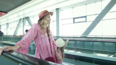 Genç çekici kadın gezgin Havaalanındaki yürüyen merdiven üzerinde yükselir