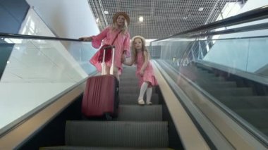 Yazlık elbise ve Havaalanındaki yürüyen merdiven aşağı gidiş lettle kızı mutlu beyaz anne