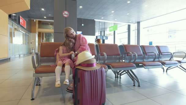 Young woman and her little daughter together have rest in the waiting room at the airport — Stock Video