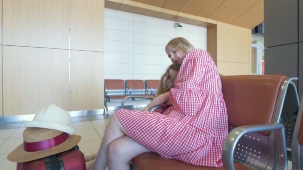 Милая маленькая девочка лежит на коленях у матерей в приемной в аэропорту — стоковое видео