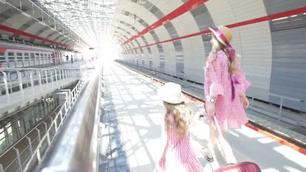 Jovem mulher atraente com mala e sua filha bonita na estação ferroviária ir para o trem — Vídeo de Stock