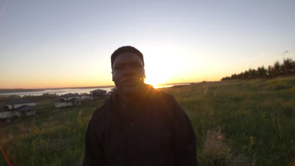 Giovane uomo africano che fuma nel campo estivo serale al bel tramonto — Video Stock