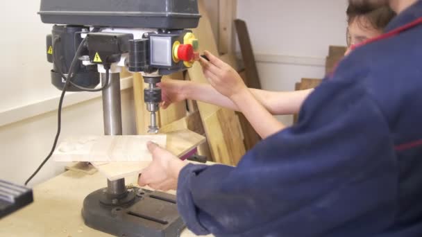 Padre e hijo taladran el tablón de madera utilizando la máquina de carpintería en el taller de carpintería — Vídeos de Stock