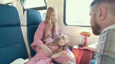 Genç beyaz aile seyahat birlikte - anne, baba ve küçük kızı pencerenin yakınındaki tren konuşan