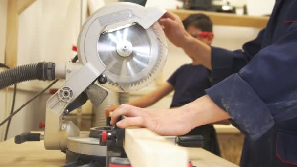 Timmerman toont de jongen hoe te snijden van houten onderdelen van schrijnwerkerij workshop — Stockvideo