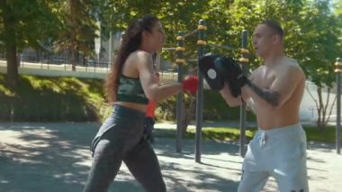 Genç adam güzel bir kadın boks açık havada güneşli gün darbeler öğretir