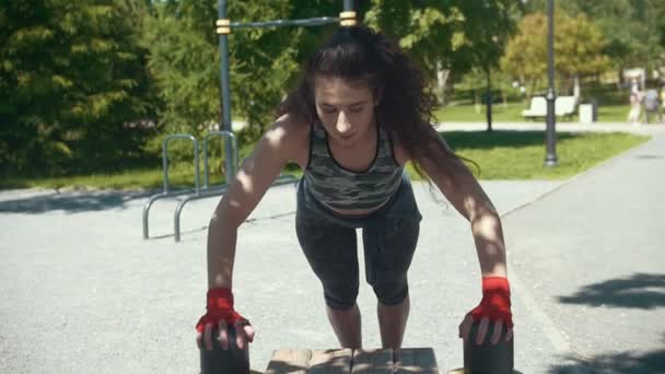 Ung brunett kvinna gör armhävningar från bänken på solig dag utomhus - slow motion — Stockvideo