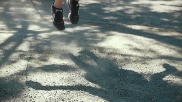 Füße einer jungen schlanken Frau springen mit einem Seil, Boxtraining im Freien an sonnigen Tagen — Stockvideo