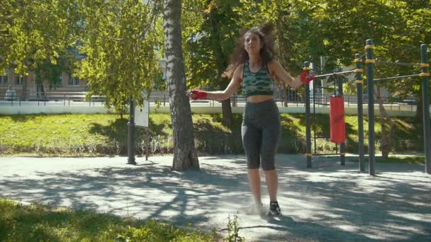 Mladá štíhlá žena skákání s lanem, trénink boxu venku za slunečného dne — Stock video