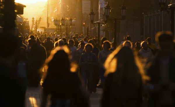 Silhuetas de pessoas multidão andando pela rua à noite de verão, luz bonita ao pôr do sol — Fotografia de Stock