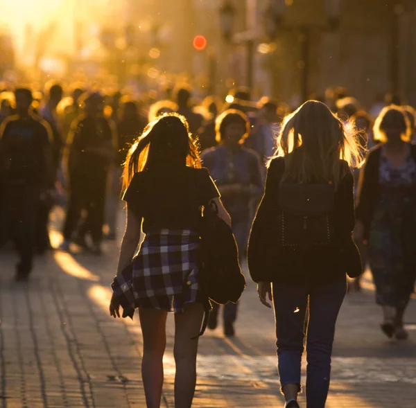 Duas jovens mulheres andando na multidão na rua pedonal no pôr do sol de verão — Fotografia de Stock