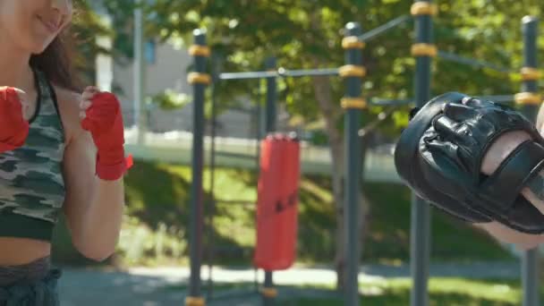 Jovem muscular homem e mulher envolvidos no boxe no parque ar ensolarado dia — Vídeo de Stock