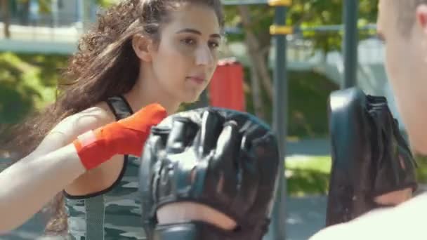 Портрет молодой женщины в спортивной одежде на тренировке по боксу в летнем парке — стоковое видео
