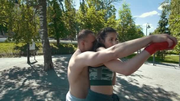 Retrato de un joven sosteniendo a una mujer por detrás, posando un puñetazo de boxeo, cámara lenta — Vídeos de Stock