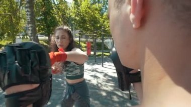 Genç adam güzel bir kadın boks açık havada güneşli gün darbeler öğretir