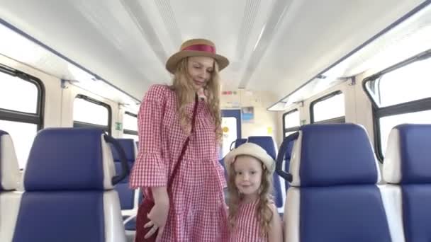 Madre e hija pequeña en los mismos vestidos camina en vagón de tren vacío — Vídeo de stock