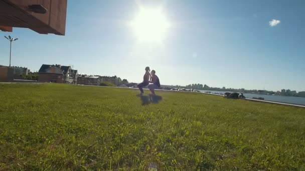 Jeune couple pratiquant des acrobaties effectuant des cascades à l'extérieur au coucher du soleil — Video