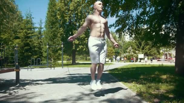 Sportieve jongeman springen met een touw in de zomer park — Stockvideo