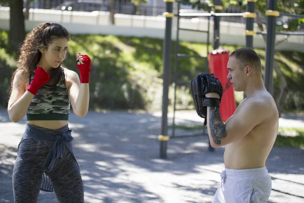 Genç kaslı adam ve park ar güneşli gün boks yapan kadın