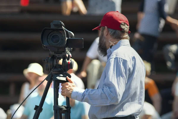 Güneşli bir gün bir video çekim gür sakal ile kap olgun profesyonel kameraman