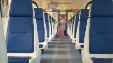 Neşeli küçük kız annesiyle boş tren arabaya yürür