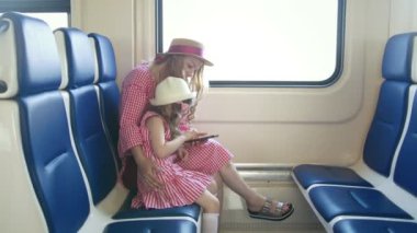 Tren ve cep telefonuyla Genç beyaz anne ve kızı silah binmek