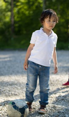 Güneşli gün futbol topu parkta oynarken sevimli beyaz yürümeye başlayan çocuk