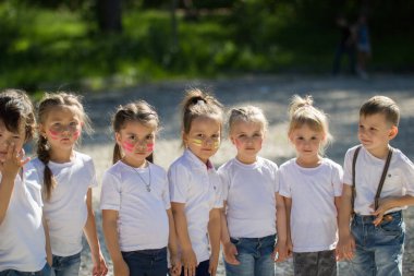 Beyaz t-shirt ile boyalı yüzler yaz günde sıraya dizilmiş küçük çocuklarda Grup