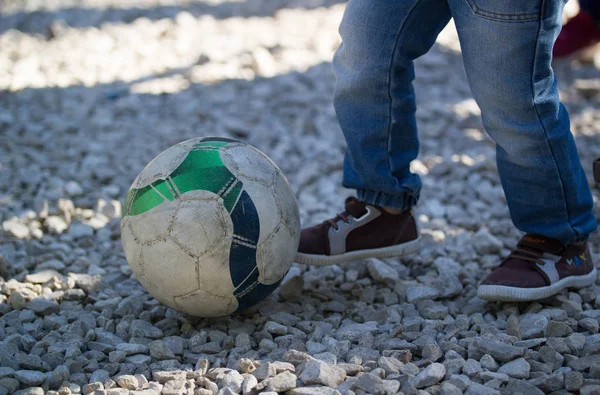 Picioarele unui băiețel lovește o minge de fotbal în aer liber la o zi însorită — Fotografie, imagine de stoc