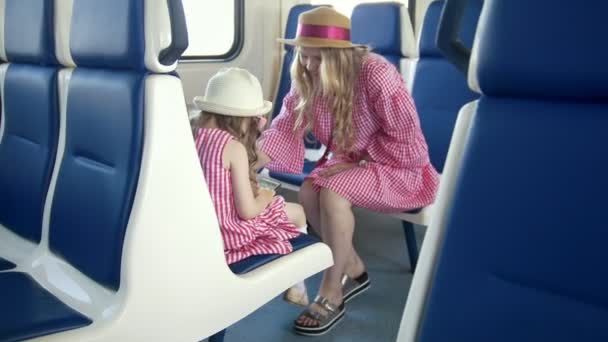 小女孩用智能手机坐在她妈妈的前面在火车上 — 图库视频影像