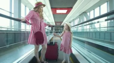 Yürüyen merdiven ve güzel kızı gidiş bavul genç çekici kadın annesi sonra havaalanında çalışır.