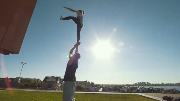 Young couple practicing acrobatics performing stunts outdoors at sunset — Stock Video