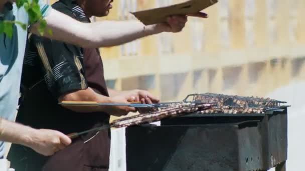 Händerna på männen grillning kebab på grill utomhus — Stockvideo