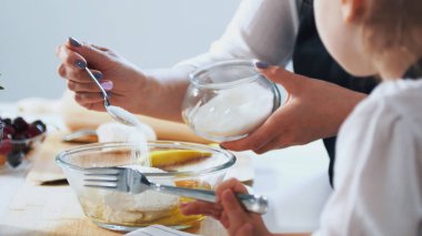 Kadın çocuğunu ile hamur krep hazırlamaya şeker koyar