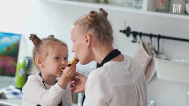 Neşeli küçük kız annesi ile birbirine ev yapımı kek besleme