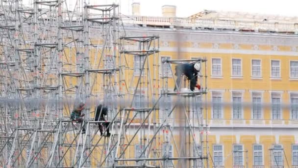 Trabalhadores da construção em chapéus duros a montar o palco na rua — Vídeo de Stock