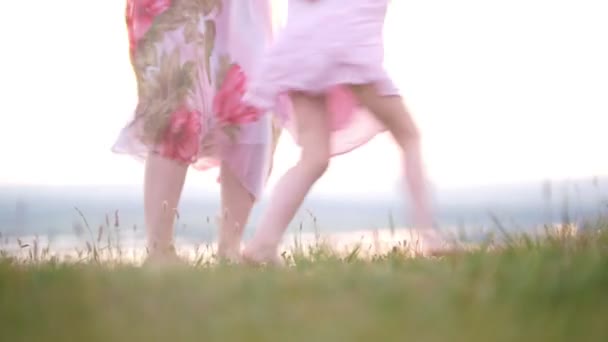 Madre e hija piernas descalzas corriendo divirtiéndose en la hierba al atardecer de verano — Vídeo de stock
