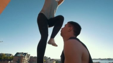 Flip gerçekleştirme genç akrobatik çift genç adam bir kadın kollarını günbatımında açık havada Dengeleme hava atar