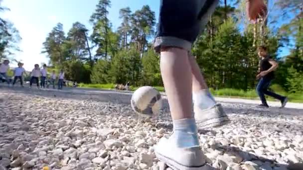 Група підлітків біжить після м'яча, граючи у двірний футбол в літній день в парку — стокове відео