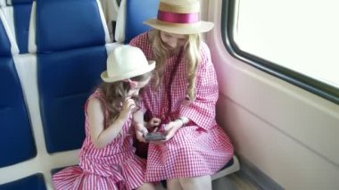 Tren ve cep telefonuyla Genç beyaz anne ve kızı silah binmek