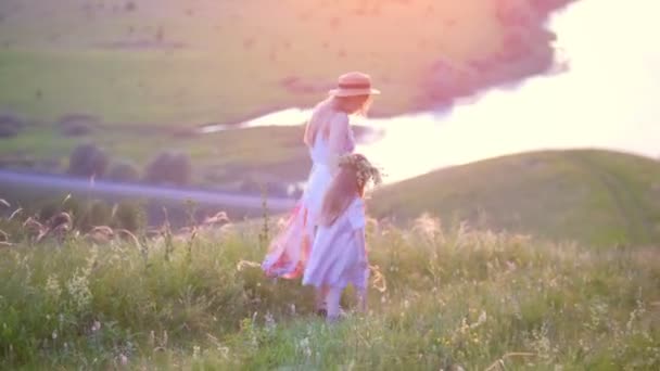 夏の夕日 望遠ショットで川の美しい景色を望む丘を歩いて手を繋いでいる娘を持つ母 — ストック動画