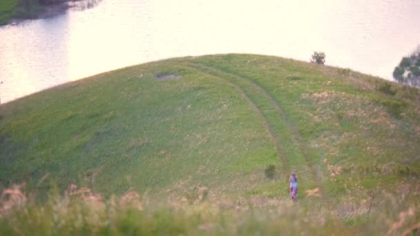 Jonge vrouw met dochtertje weglopen van de heuvels bij zonsondergang zomer — Stockvideo