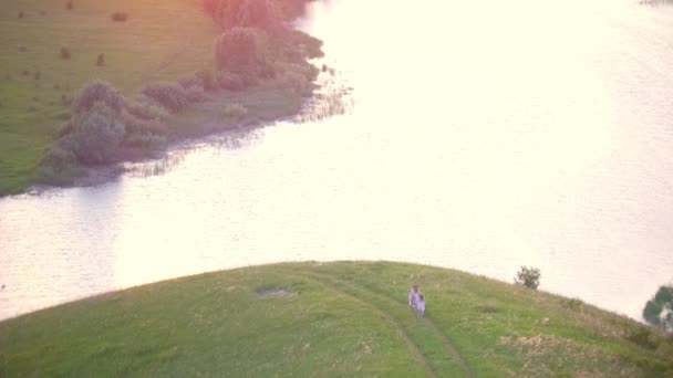 Luchtfoto van de heuvel - moeder en dochtertje plezier op de weide bij zonsondergang zomer — Stockvideo