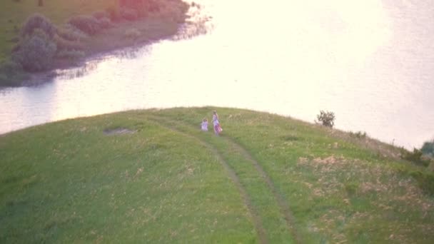 Vista aérea - menina com sua mãe tem um descanso na colina perto do rio — Vídeo de Stock