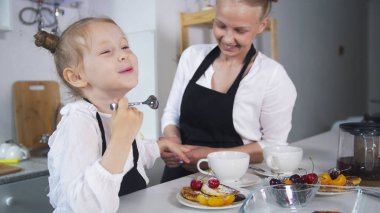 Küçük beyaz kız annesiyle birlikte mutfakta yemek