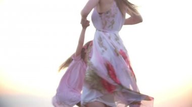 Küçük kız annesiyle yaz akşamları tepe üzerinde çim eğleniyor yalınayak