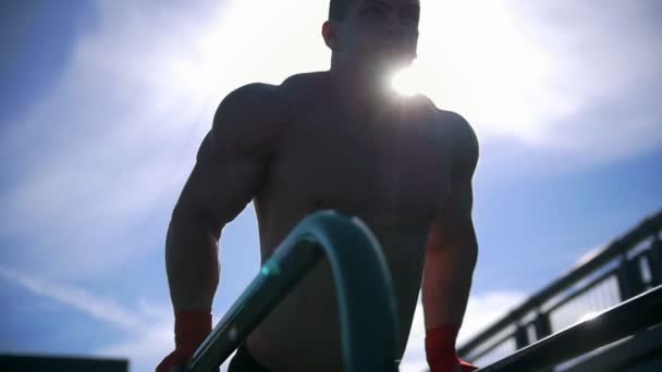 Giovane sportivo muscoloso che spinge sui paralleli - allenamento in estate all'aperto, rallentatore — Video Stock