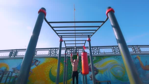 El hombre musculoso fuerte tiene entrenamiento en barras horizontales al aire libre — Vídeos de Stock